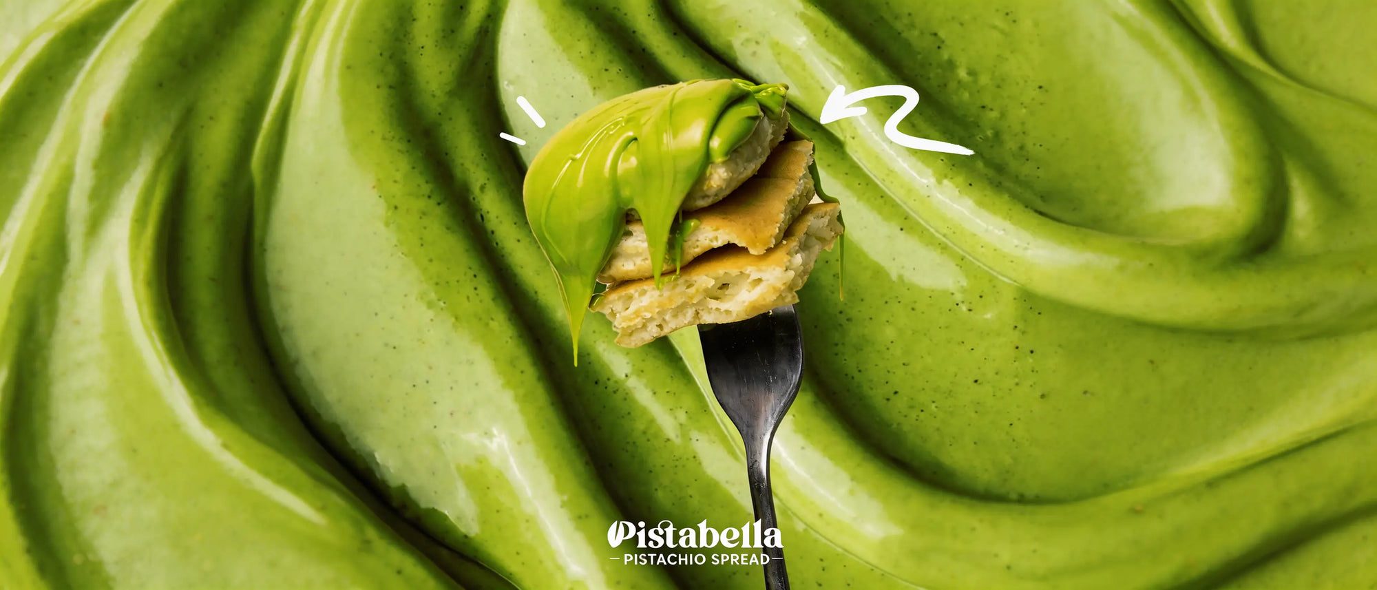 Vivid natural green Pistabella pistachio spread swirled across a surface, with a spread cracker on a fork.